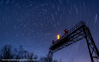 Twenty-Seven and a half minutes elapse in this collection of four shots layered together as the Pennsy signal bridge at AR (Allegheny Range) stands tall against the backdrop of the swirling night sky and the North Star. This signal stands close to the Pennsylvania Railroad's summit across the Eastern Continental Divide 2,167 feet above sea level and lets eastbound crews know half the journey over the mountains is complete before they enter Portage Tunnel and into "The Slide" and down the mountain.